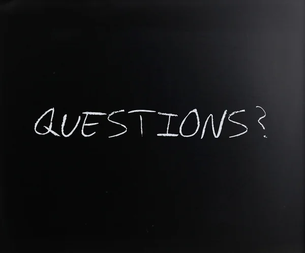 "Frågor? "handskriven med vit krita på en svart tavla — Stockfoto