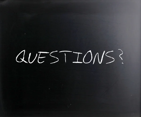 "Questions?" handwritten with white chalk on a blackboard — Stock Photo, Image