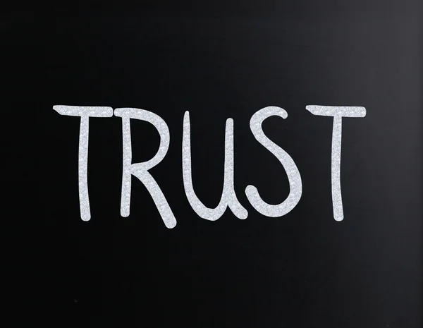 The word "Trust" handwritten with white chalk on a blackboard — Stock Photo, Image