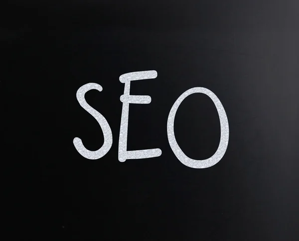The word "SEO" handwritten with white chalk on a blackboard — Stock Photo, Image