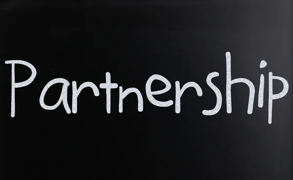 Слово "Партнерство" написано от руки белым мелом на блекбо — стоковое фото