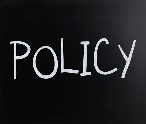 Ordet "policy" er håndskrevet med hvit kritt på tavlen. – stockfoto