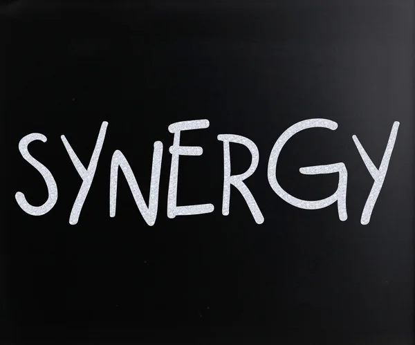 Ordet "synergy" handskrivna med vit krita på en svart tavla — Stockfoto