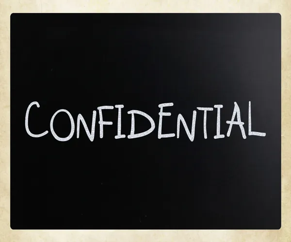 Le mot "confidentiel" écrit à la main avec de la craie blanche sur un noir — Photo