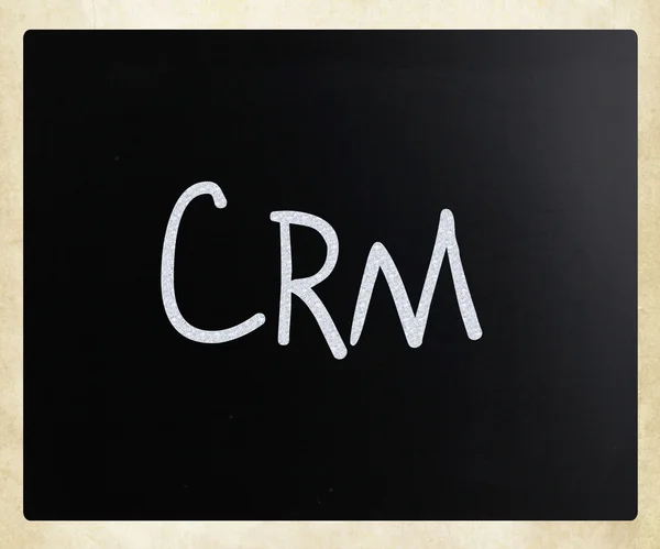 Le mot "CRM" écrit à la main à la craie blanche sur un tableau noir — Photo