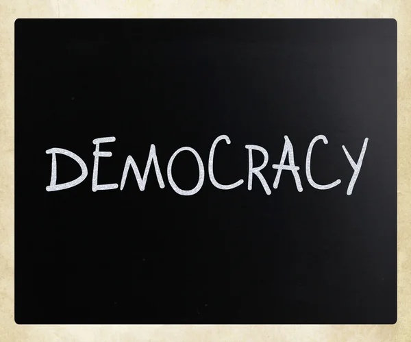The word "Democracy" handwritten with white chalk on a blackboar — Stock Photo, Image
