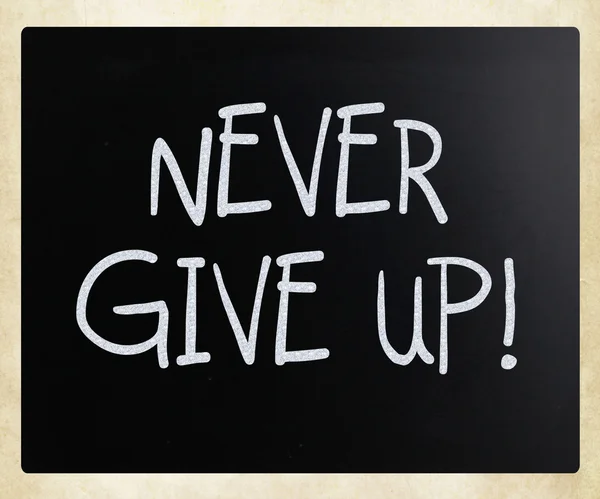 "Never give up" handwritten with white chalk on a blackboard — Stock Photo, Image