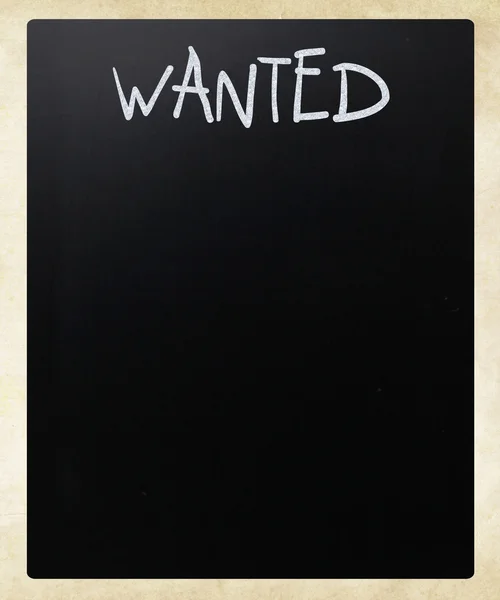 "Wanted "handwritten with white chalk on a blackboard — стоковое фото