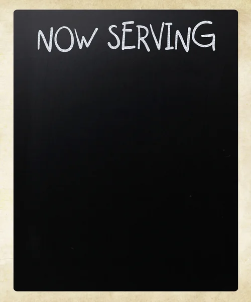 "Agora servindo "manuscrito com giz branco em um quadro-negro — Fotografia de Stock