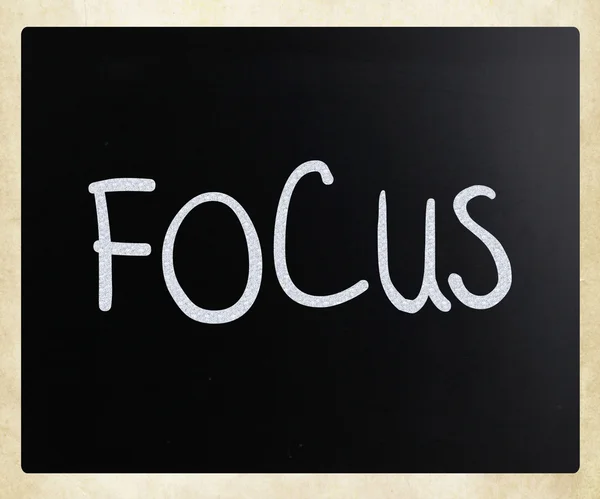 Ordet "fokus" handskrivna med vit krita på en svart tavla — Stockfoto