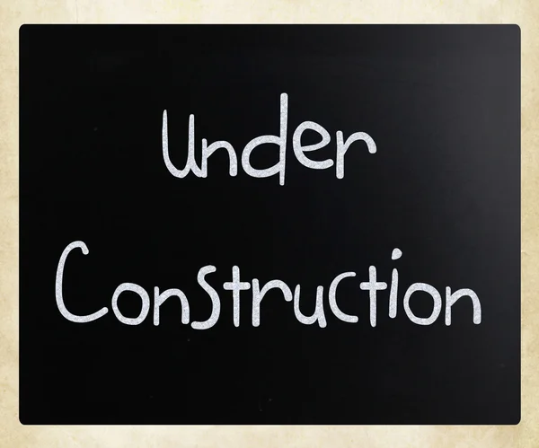"Under construction" handwritten with white chalk on a blackboar — Stock Photo, Image