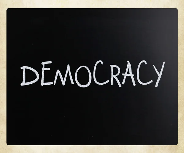 The word "Democracy" handwritten with white chalk on a blackboar — Stock Photo, Image