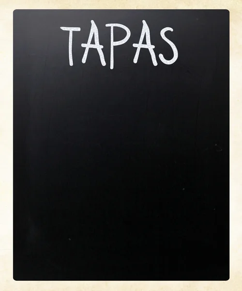 "Tapas" handwritten with white chalk on a blackboard — Stock Fotó