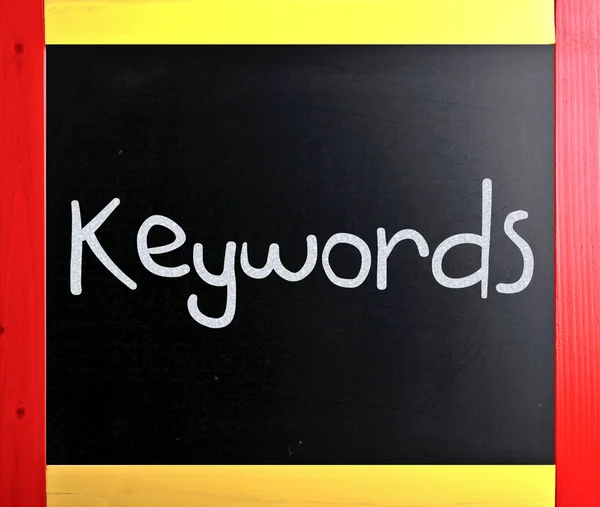 A "Kulcsszavak" fehér krétával egy táblára kézzel írott szó — Stock Fotó
