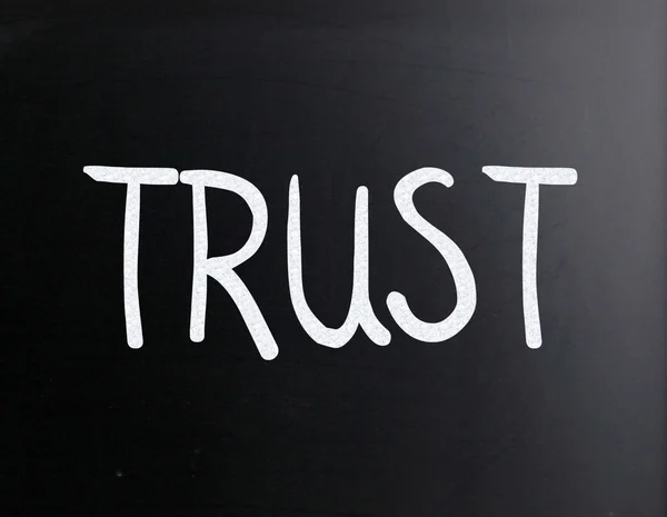 Le mot "Trust" écrit à la main à la craie blanche sur un tableau noir — Photo
