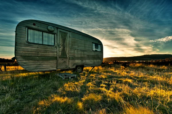 Camper trailer retroiluminado pelo sol durante um belo pôr do sol — Fotografia de Stock