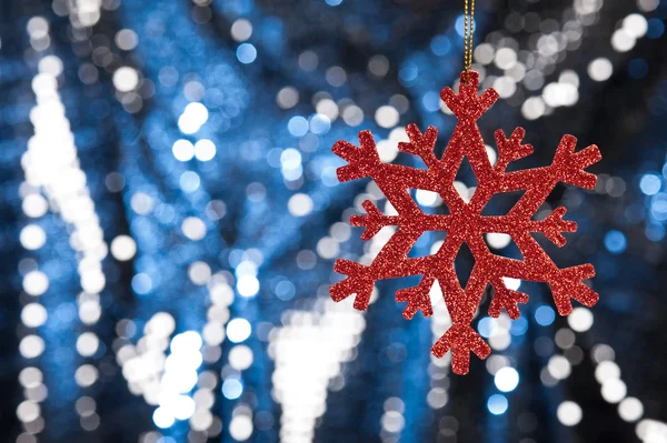 Red snow flake on a blue, silver glitter background — Stock Photo, Image