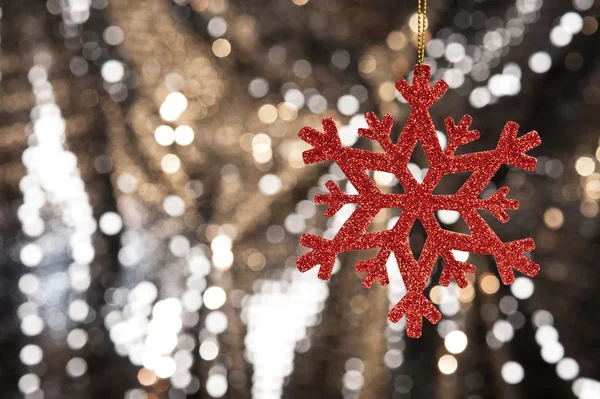 Floco de neve vermelho em um fundo de brilho dourado — Fotografia de Stock