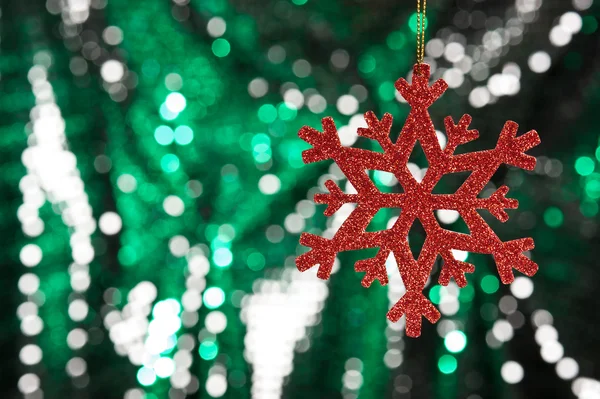 Red snow flake on a green, silver glitter background — Stock Photo, Image