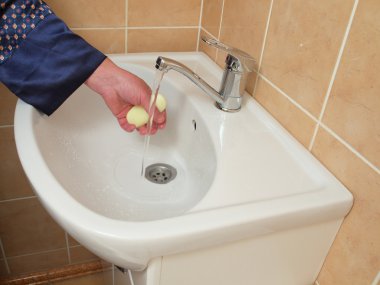 A person washing their hand in the bathroom sink . clipart