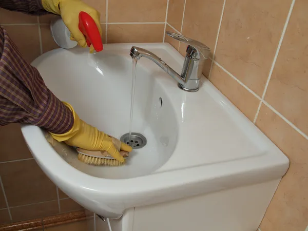 bir kişi bir eldiven ile banyo lavabo temizlik