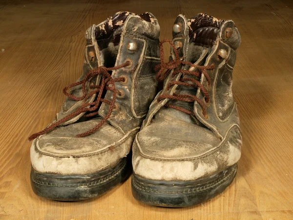 Die alten abgewetzten Stiefel mit den braunen Schnürsenkeln auf hölzern bis zum Fußboden. — Stockfoto