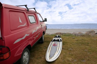 Windsurfers van and board at beach clipart