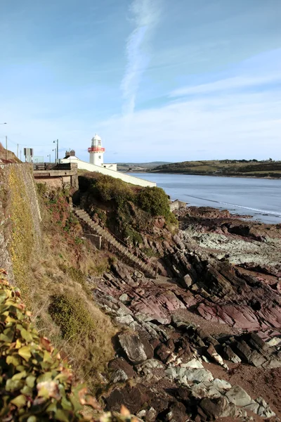 Maják s schody až na skalnaté pláži během slunečného dne — Stock fotografie