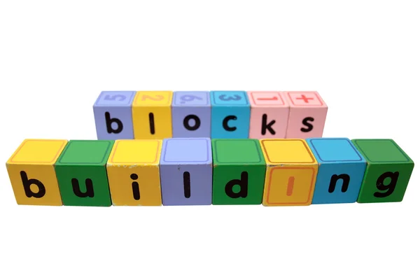 Yapı taşları olarak oyuncak blok harfler beyaz karşı oynamak. — Stok fotoğraf