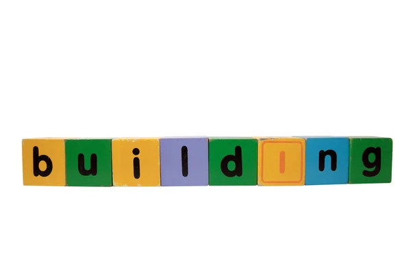 Building in wood play block letters against white — Stock Photo, Image