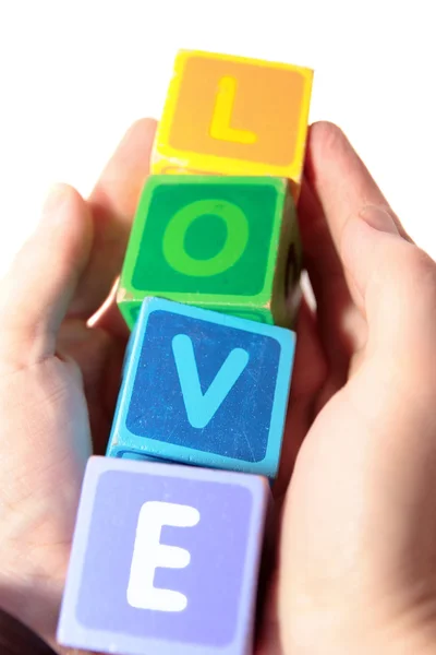 Kärlek i trä spela blockerar bokstäver i händerna — Stockfoto