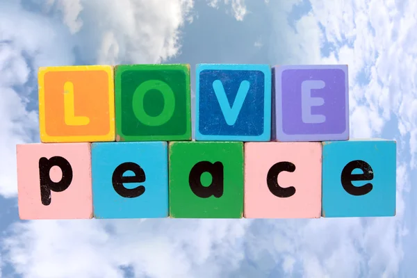 Kärlek på fred i trä spela textas mot molnen — Stockfoto