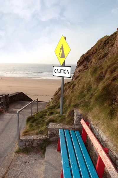 Bench and beach landslide caution sign — Stock Photo, Image