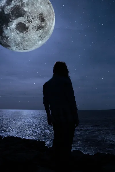 Silueta de una triste mujer solitaria con luna llena en el borde de un acantilado — Foto de Stock