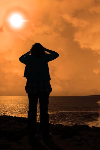 stock image Silhouette of a sad lone woman on a cliff edge