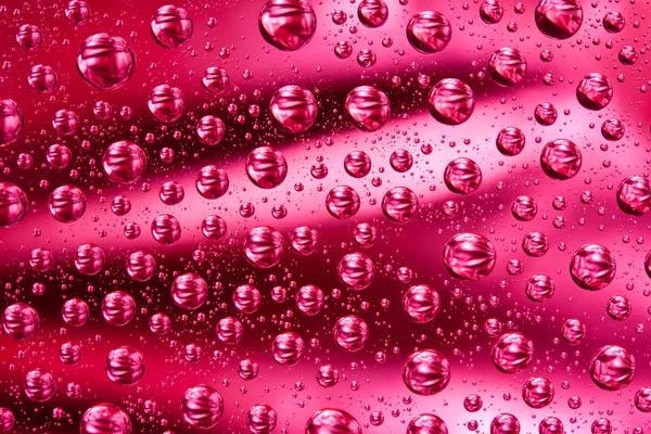 Gouttes d'eau sur la surface en verre rouge — Photo