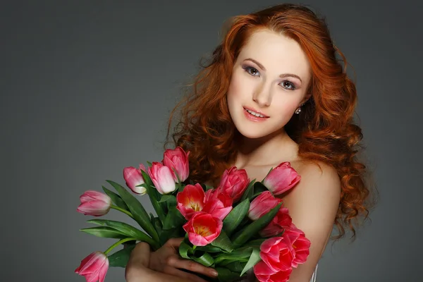 Schöne junge rothaarige Mädchen mit Tulpen — Stockfoto