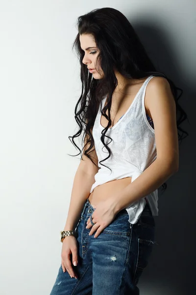Portret piękna dziewczyna seksualne w dżinsy, stojący w pobliżu biała ściana, w stylu mody, glamur — Zdjęcie stockowe