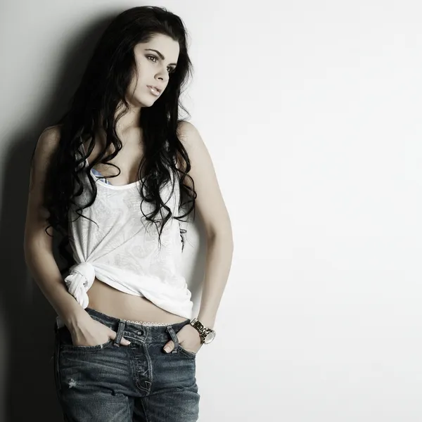Porträt eines schönen, sexuellen Mädchens in Jeans, das an einer weißen Wand steht, in modischem Stil, Glamour — Stockfoto