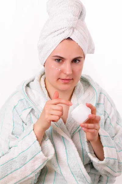 Attractive young girl lubricates her face with cream — Stock Photo, Image