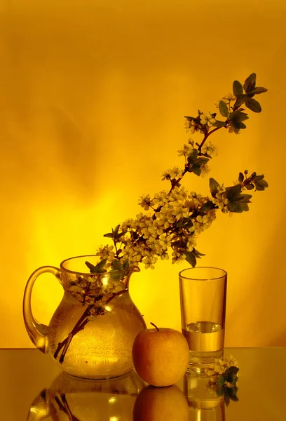 Creative composition with glass, jug, apple and flowers — Stock Photo, Image
