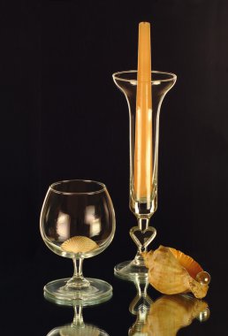 A candle in the glass candle holder, a wineglass and cockleshells clipart