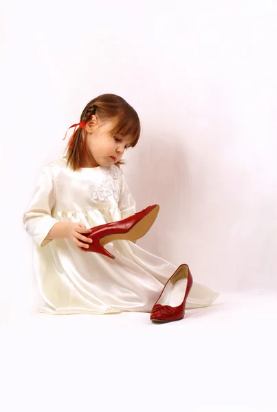 A little girl looks at the big shoes — Stock Photo, Image