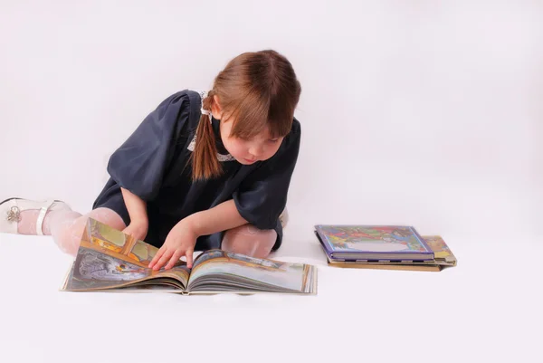 Маленькая девочка смотрит на книгу — стоковое фото