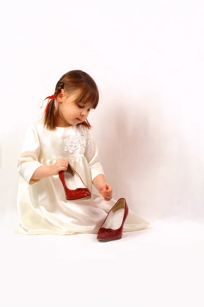 A little girl plays with big shoes — Stock Photo, Image