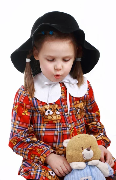 Une petite fille au chapeau joue avec un ours en peluche — Photo