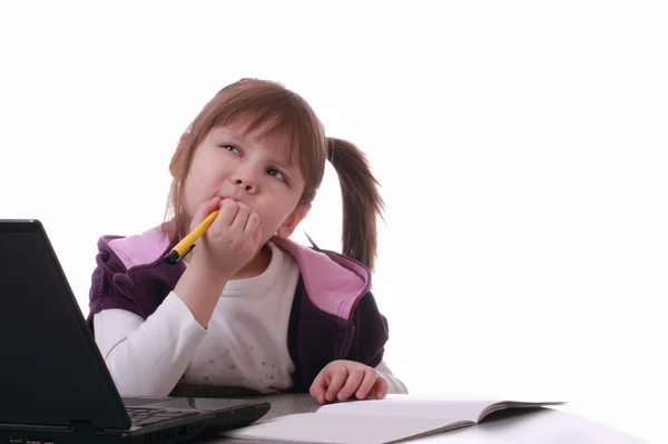 Mała dziewczynka siedzi w pobliżu laptopa i myśli — Zdjęcie stockowe