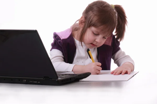 一个小女孩坐在附近的笔记本，并将写入 — 图库照片