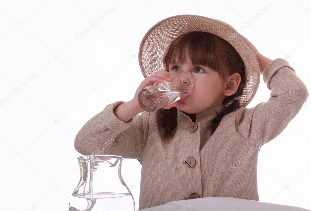 A little girl sits and drinks water from a glass