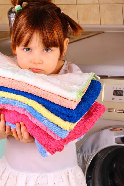 Une petite fille va laver les serviettes dans la machine à laver — Photo